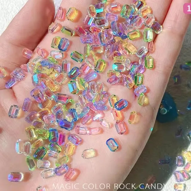 A hand displays a collection of colorful resin rock candy charms including pink, yellow, and blue hues.