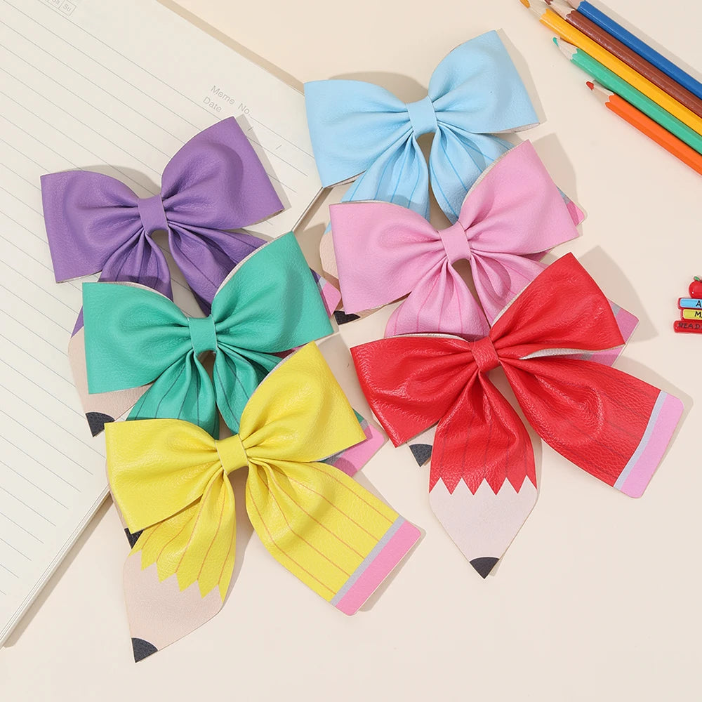 A set of colorful pencil bow hair clips featuring purple, blue, pink, and yellow ribbons.