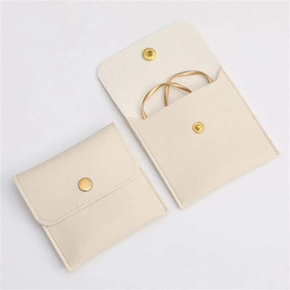 A light beige PU leather jewelry pouch with a flap closure and gold-toned snap button.