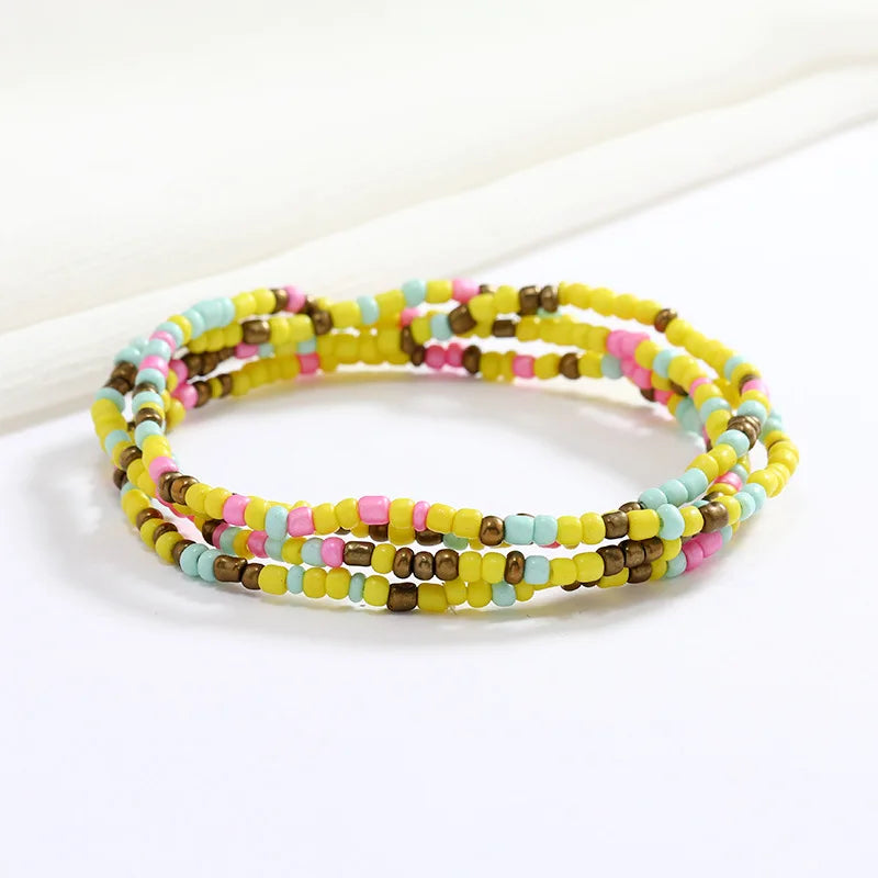 Una pila de collares hechos a mano con cuentas de colores: amarillo, rosa y turquesa.