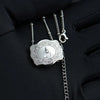Silver initial letter pendant necklace with a detailed filigree design hanging from a chain.