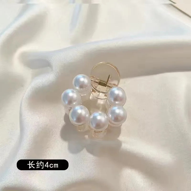 A set of simulated pearl hair claws with a silver finding and a 4cm length shown against a white satin background.
