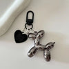 A silver cartoon dog keychain with a heart-shaped tag and a black carabiner clip.