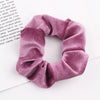 A close-up of a mauve velvet scrunchie with gathered fabric texture on a white background.