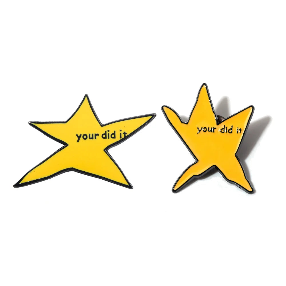Two yellow star-shaped enamel pins with the text your did it on them