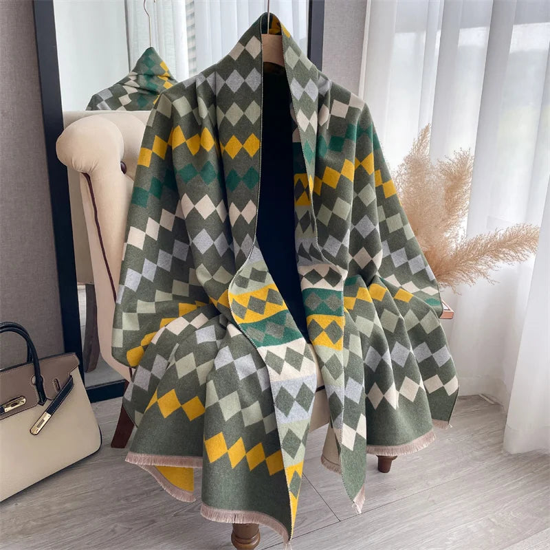 A plaid cashmere feel scarf and shawl wrap in shades of olive green, gray, and mustard yellow draped on a hanger.