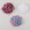A pile of colorful disposable rubber hair ties in various shades of pink, purple, blue, and yellow, next to a pile of white h