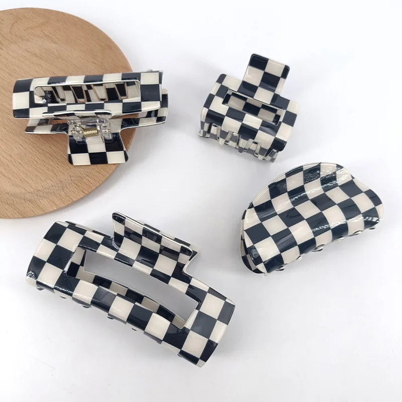 A collection of black and white checkered rectangle hair claw clips displayed on a wooden surface.