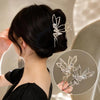 A woman is shown with a black updo featuring a delicate silver rhinestone butterfly hair clip.