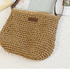 A hand-woven straw visor hat in a natural beige color resting on a white textured surface.