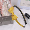 A yellow grosgrain ribbon hair bow is displayed next to a box and a framed card.