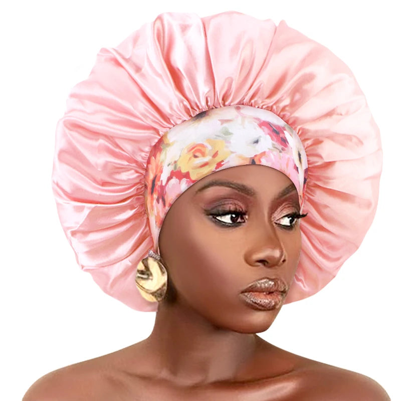 A model wears a pink satin sleep bonnet with an elastic band on her head.