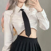 A woman wearing a white cropped shirt, black tie, and black pleated skirt.