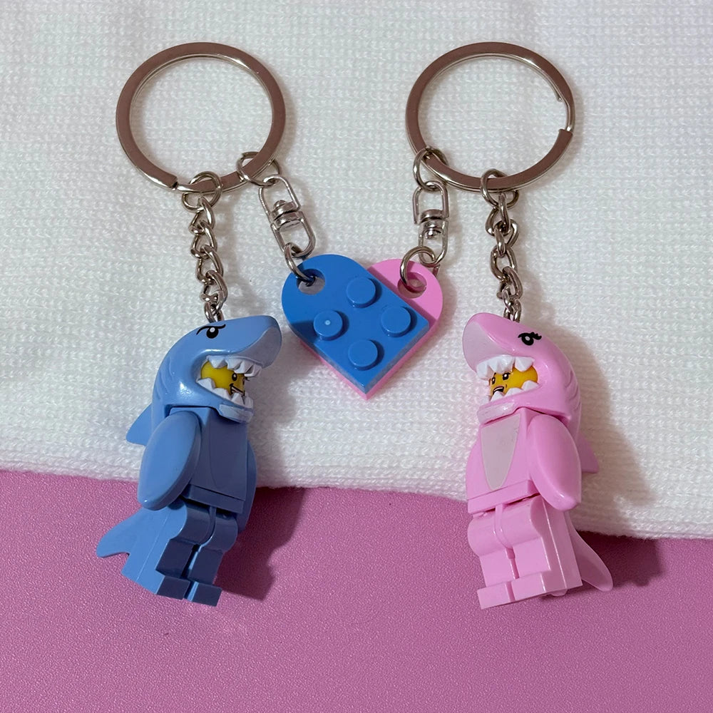 A set of couple shark keychain charms shaped like heart-shaped building blocks in blue and pink.