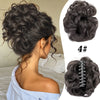 A close-up of a woman's hair styled in a voluminous curly messy bun with a claw clip, showing the texture and volume.