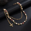 Gold chain necklace featuring pearl and ruby beads with a cross pendant.