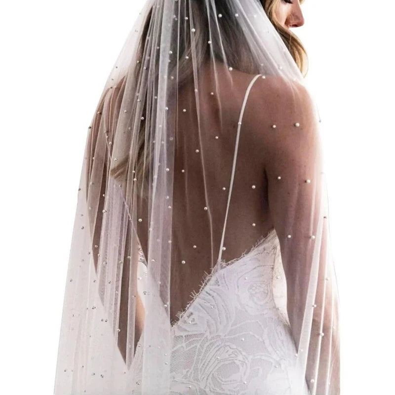 Una novia vistiendo un velo de perlas y encaje para su vestido de novia desde atrás.