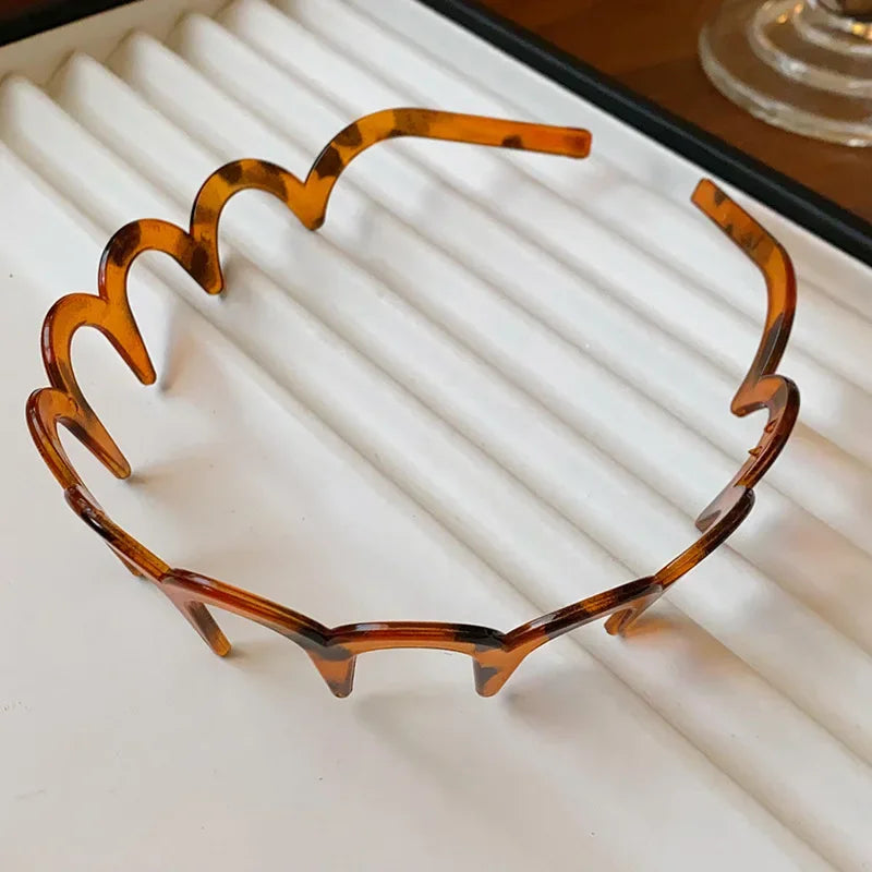 A brown resin wave toothed headband for women displayed on a white surface.