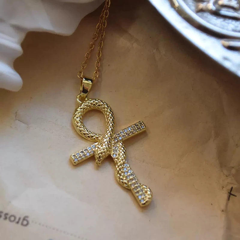 A gold-toned dainty cross charm necklace with a textured link and a diamond-encrusted cross pendant.