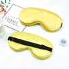 A golden silk sleep mask with a black strap is shown next to a box labeled Chanel.