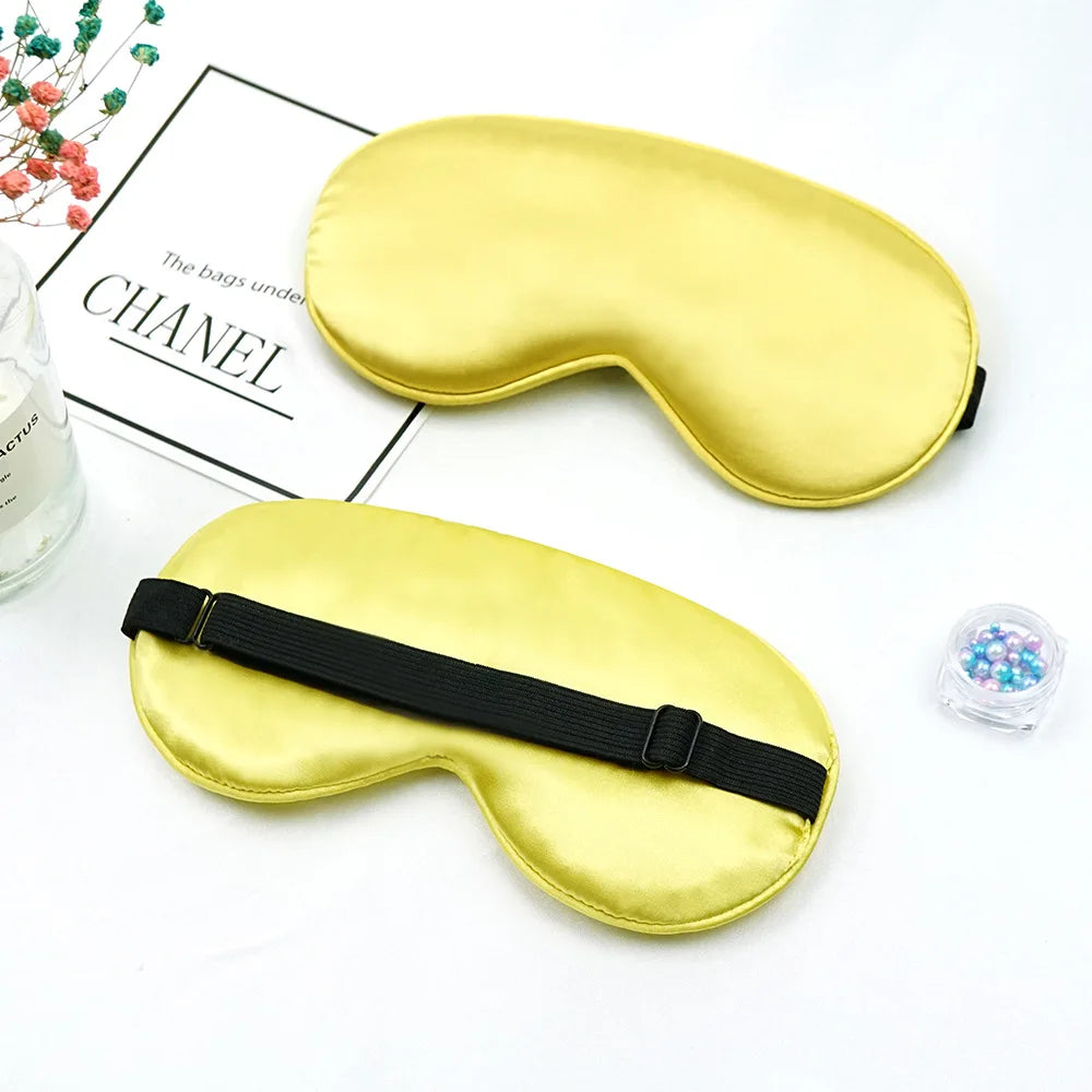 A golden silk sleep mask with a black strap is shown next to a box labeled Chanel.