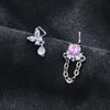 Une paire de anneaux à nez en acier inoxydable en forme de L avec un motif de fleur scintillante et un cœur de pierre rose.