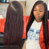 Una mujer muestra una larga peluca de encaje bordado color borgoña suelta, con el cabello peinado en trenzas tipo box.