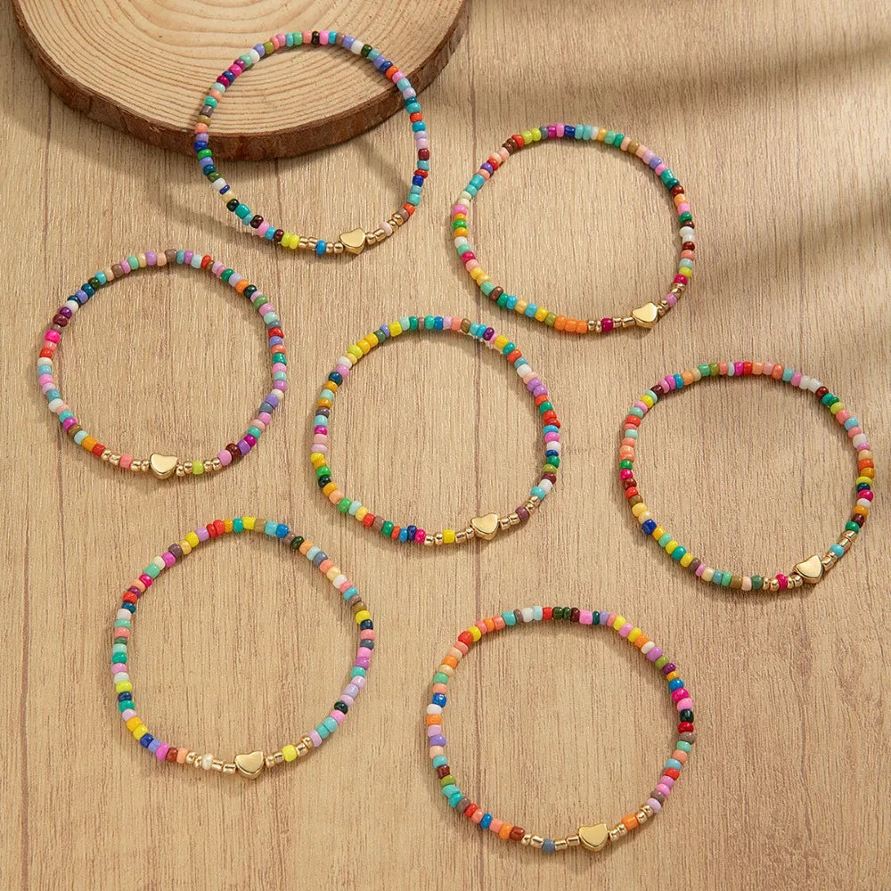 A collection of colorful resin beaded bracelets arranged on a light wooden surface.