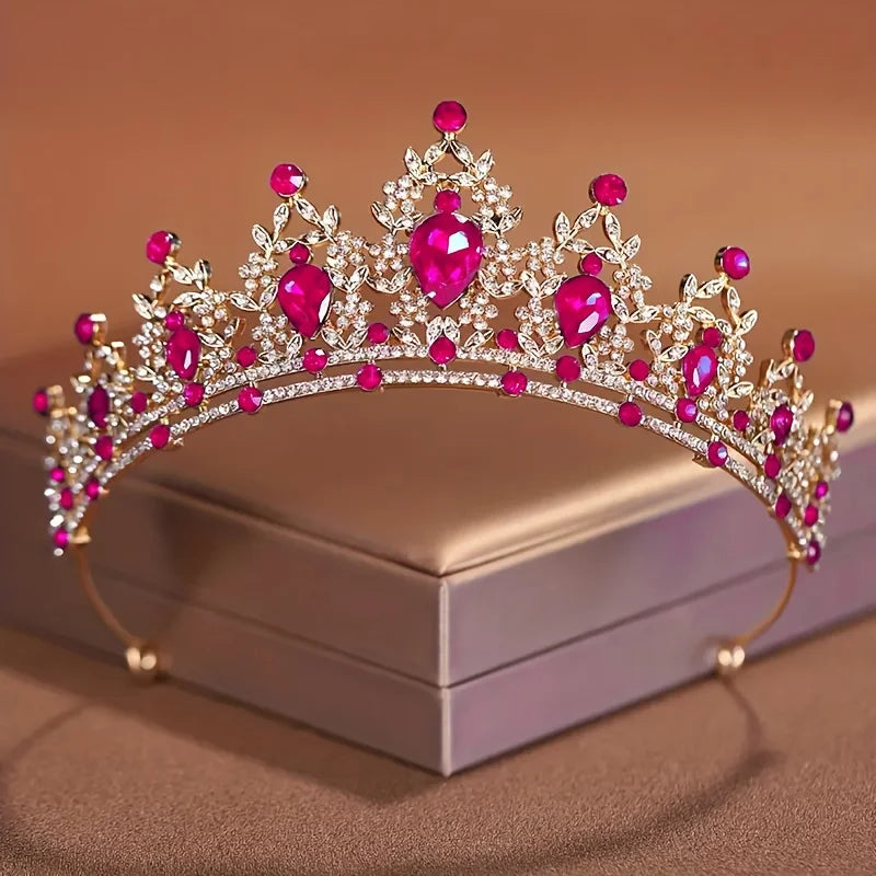Diadema de cristal rosa brillante y transparente con diseño de corona, mostrada en una caja.