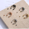 Sammlung von Edelstahl-Nasepiercing-Ringen in verschiedenen Größen und Finishes auf einem hellen Steinuntergrund