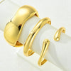 A set of three gold geometric wave bangles displayed on a white background.