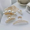 Gold-toned simulated pearl hair claws displayed on a white surface.