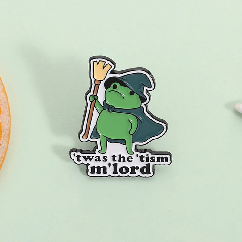Insignia de esmalte con un mago rana verde con sombrero puntiagudo y vara, con el texto 'was the tism mlord' debajo.