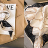 A cream and beige floral print silk scarf draped on a tan blazer.