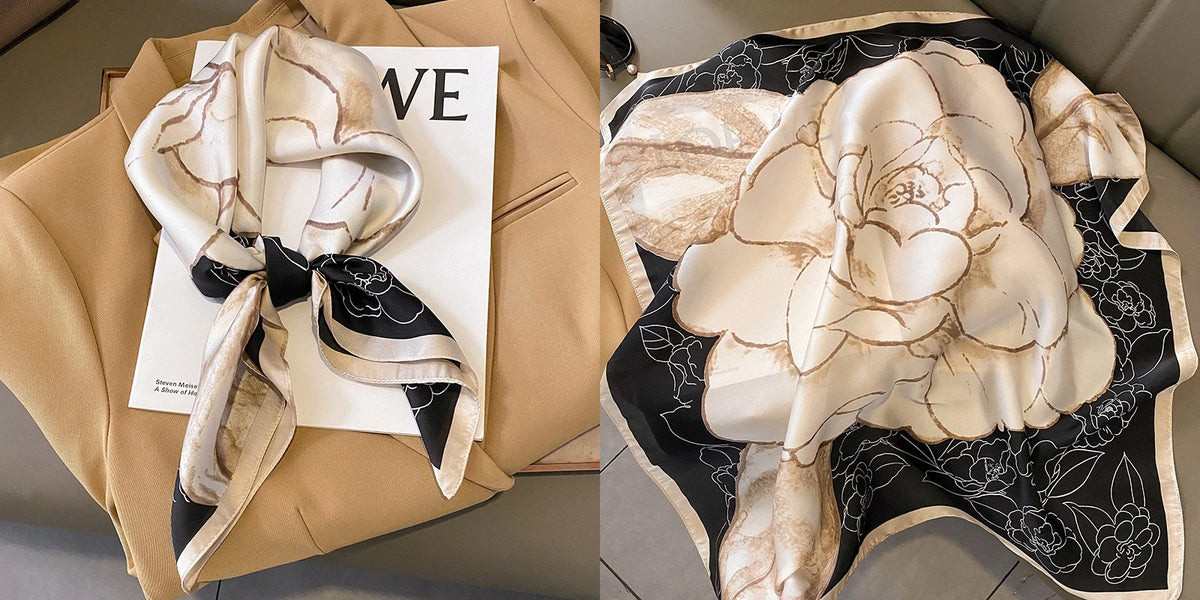 A cream and beige floral print silk scarf draped on a tan blazer.