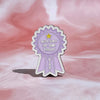A purple enamel pin shaped like a ribbon award with the text Got Out Of Bed Today and a star.