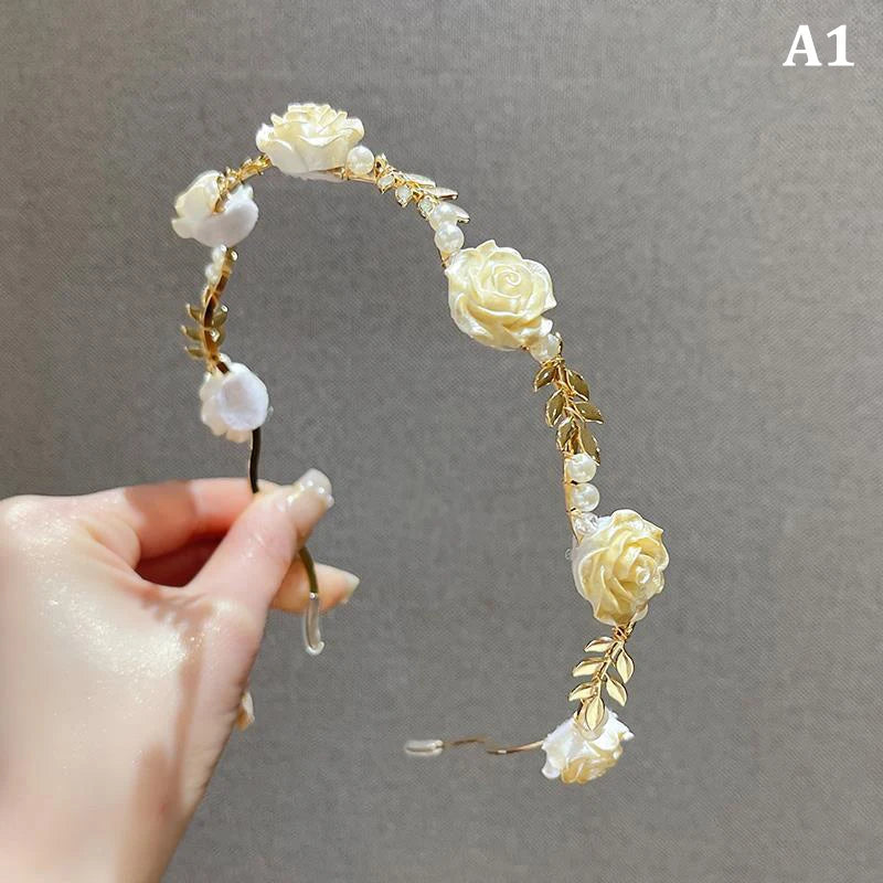 A close-up of an elegant rose vine headband hair accessory made of white and gold floral elements.