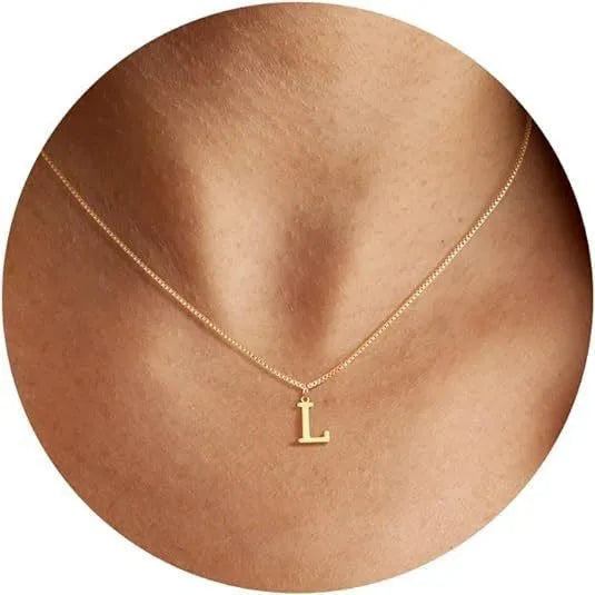 A close-up of a gold plated alphabet initial necklace with the letter L worn on a person's neck.
