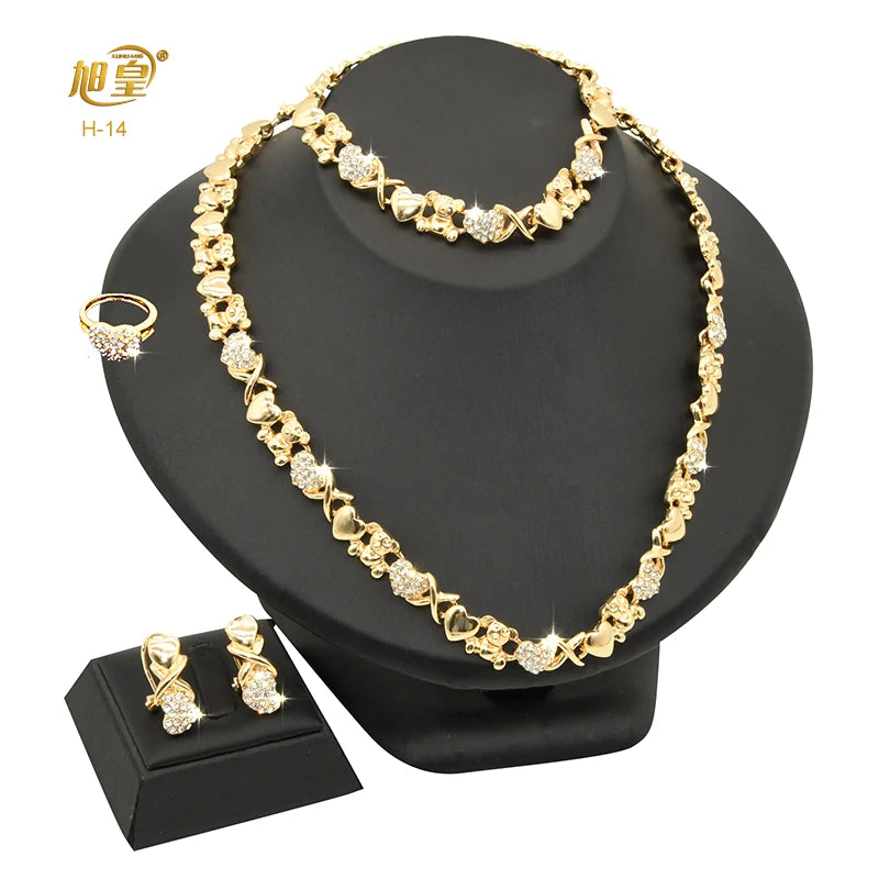 A gold heart crystal jewelry set featuring a delicate necklace and earrings displayed on a black stand.