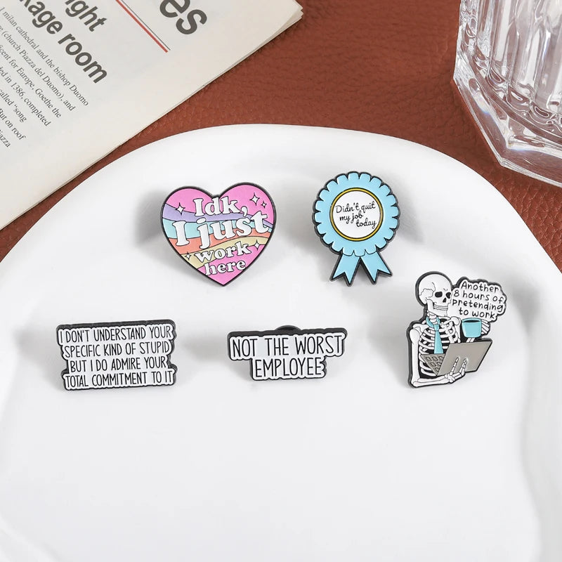 A collection of enamel pins featuring funny work quotes and sentiments on a white plate.