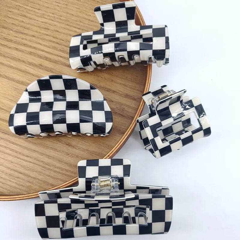 A collection of black and white checkered rectangle hair claw clips arranged on a wooden surface.