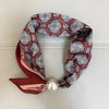A maroon and white patterned scarf tied with a satin ribbon and finished with a pearl tail magnetic clasp.