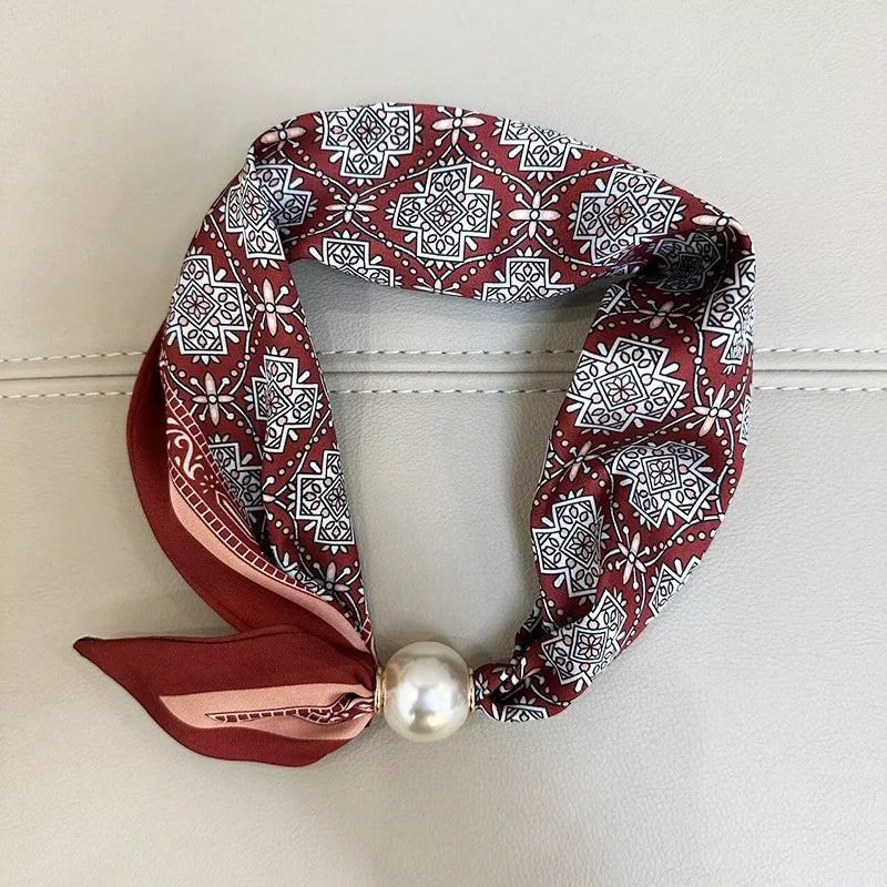A maroon and white patterned scarf tied with a satin ribbon and finished with a pearl tail magnetic clasp.