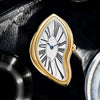 A close-up of a gold-toned fashion quartz wristwatch with a white dial and Roman numerals set against a dark background.