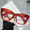 A pair of bright red, translucent cat eye sunglasses resting on a white surface.