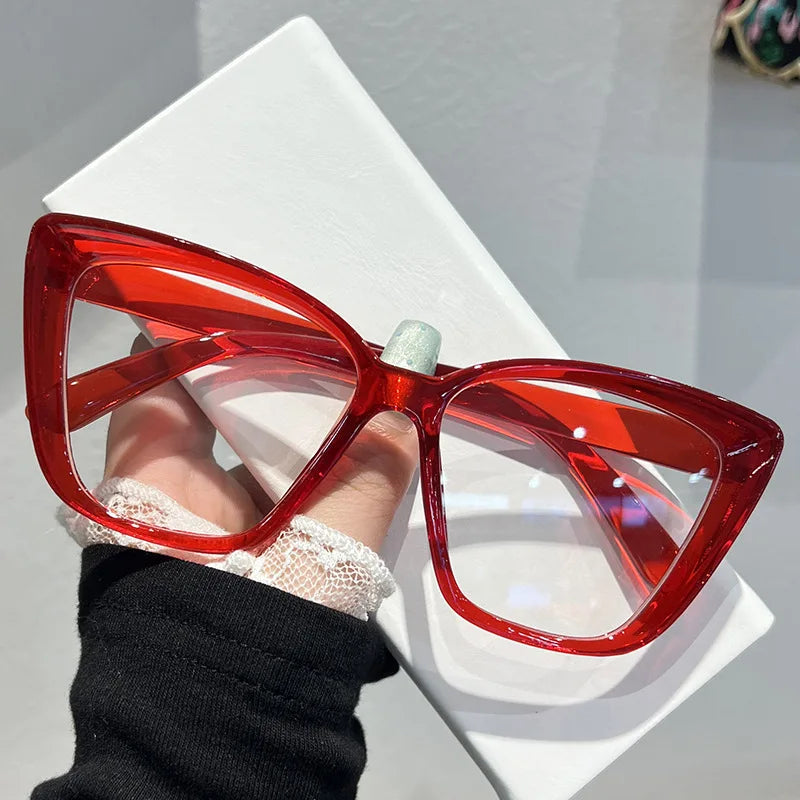 A pair of bright red, translucent cat eye sunglasses resting on a white surface.