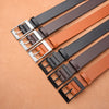 A collection of men's luxury PU leather belts in black and tan colors with silver metal pin buckles.
