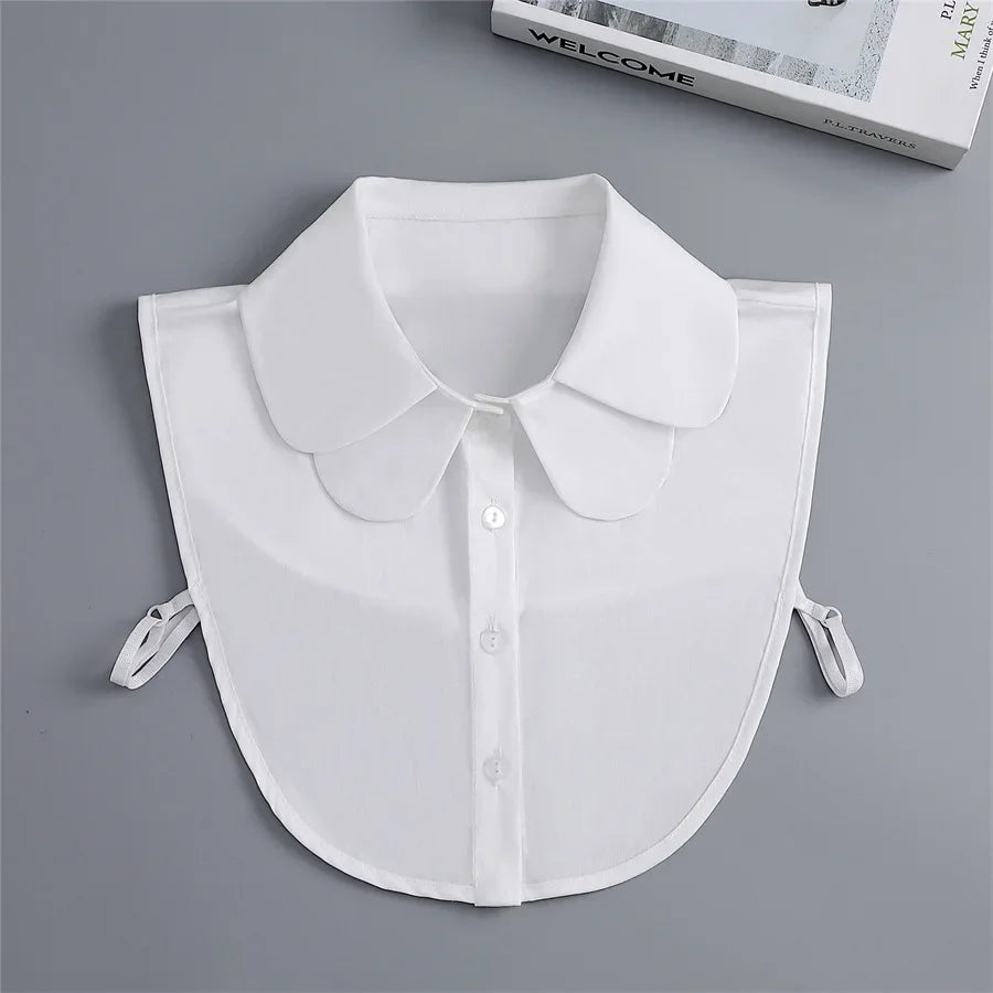 White fashion blouse with a false collar and detachable neckline shown flat lay.