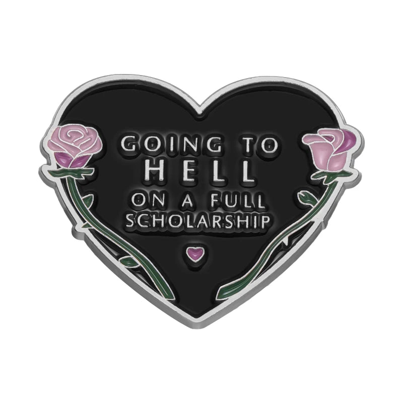 Pin de esmalte con forma de corazón negro que muestra la frase 'Iré al infierno con una beca completa' rodeada de rosas.