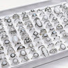 A collection of silver and white stone charm rings for women displayed in a white box.